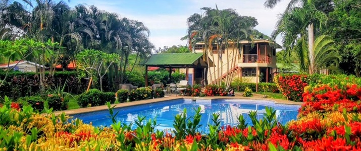 Piscine bordée de fleurs, avec maison en arrière plan